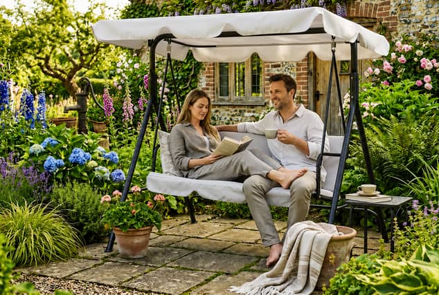 The three-seater swing chair includes an adjustable canopy and cushioned seating for relaxed garden afternoons