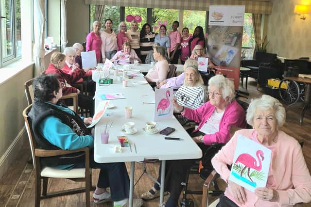 A vibrant moment as Cliftonville Care Home residents and staff pose with their completed artworks from the Wear It Pink: Coffee & Paint art wellbeing session by @ArtExpressionsUKCIC
