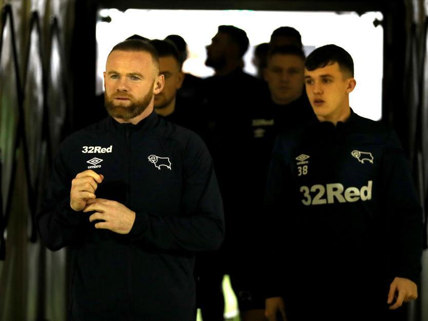 Wayne Rooney leads the Cobblers players out for their pre-match stroll on the PTS Academy Stadium pitch