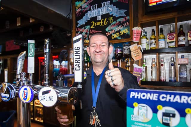 Pub landlord Darren gives a thumbs up behind his bar at Fiddlers.
