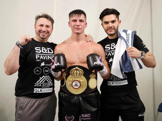 Kieron Conway shows off his title belt, flanked by his dad and trainer James (left) and Alex Le Geuvel