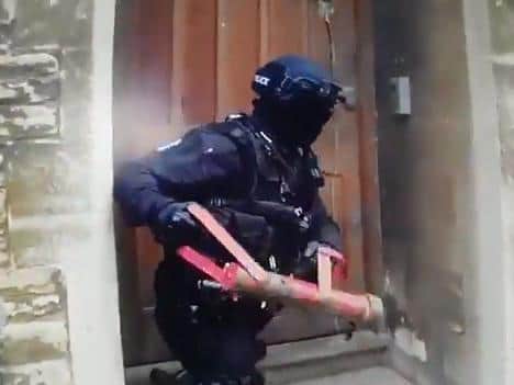A second officer finishes the job with a heavy ram as police raid the property in Billing Road