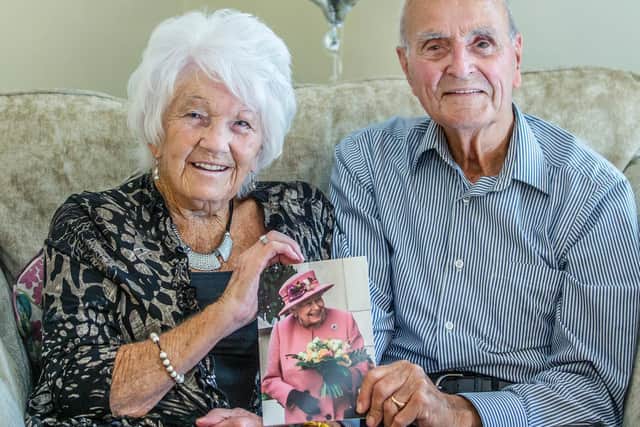 The happy couple, Joan and Roy King, pictured smiling and holding up their anniversary card from the Queen. Pictures by Kirsty Edmonds.