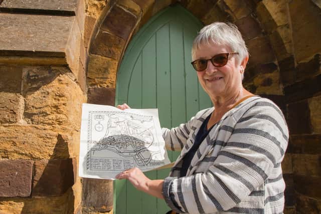 Marie Dickie from Friends of Northampton Castle outside the old postern gate with a map of what the Northampton would have looked like in the castle's heyday