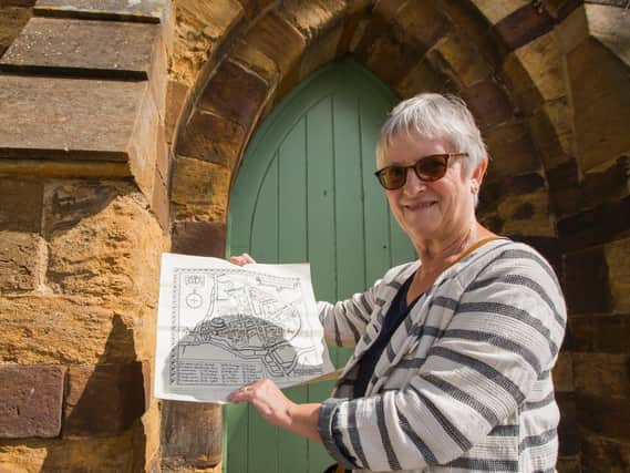 Marie Dickie from Friends of Northampton Castle outside the old postern gate with a map of what the Northampton would have looked like in the castle's heyday