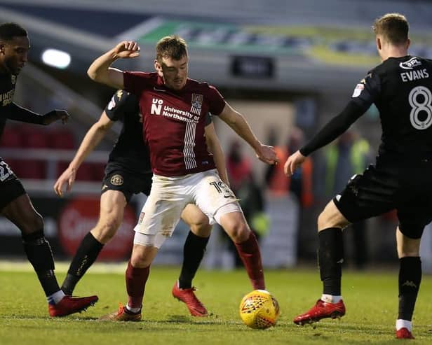 Chris Long fights for possession when Cobblers last played Wigan in January 2018.