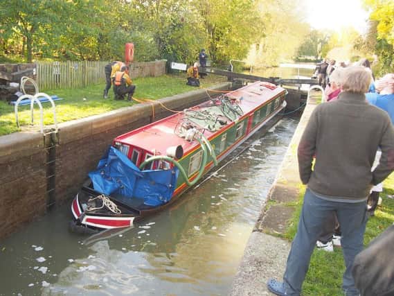The rescue team had to pump water from the narrowboat to refloat it as a small crowd gathered to watch. Photo: Mark Denton
