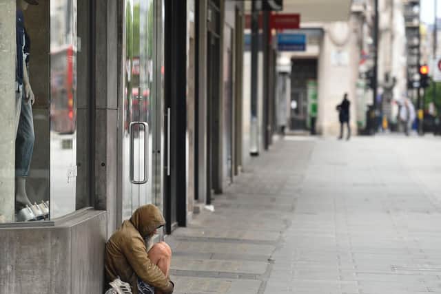 A homeless man huddles for warmth outside a shop. (Stock image).