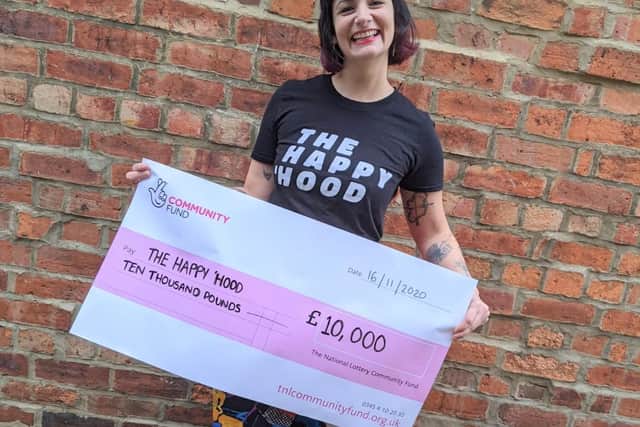 Laura Graham pictured holding up a cheque from the National Lottery, which has thrown the magazine a lifeline.