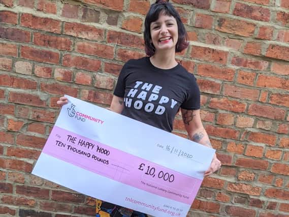 Laura Graham pictured holding up a cheque from the National Lottery, which has thrown the magazine a lifeline.