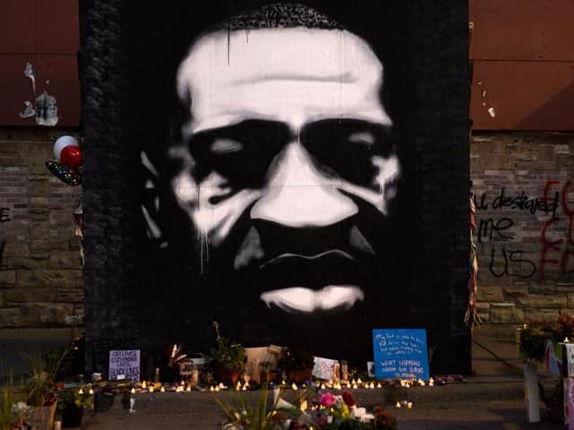LED candles are placed beneath a portrait of George Floyd during a birthday celebration for him at a memorial site known as "George Floyd Square" on October 14, 2020 / Getty Images