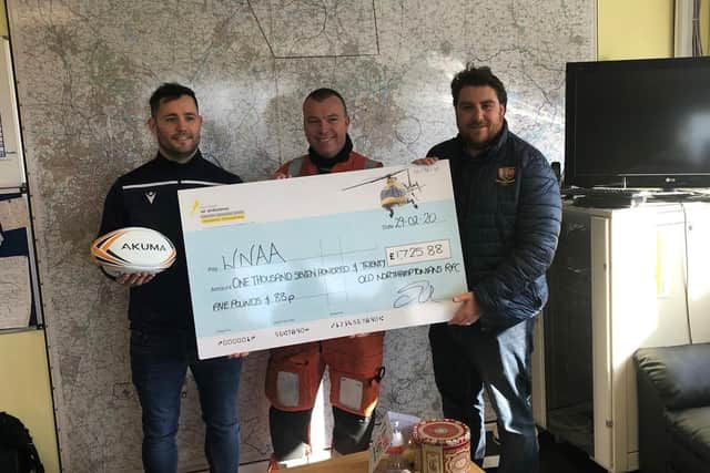 Club captain and coach presenting air ambulance with a cheque for more than 1,000.