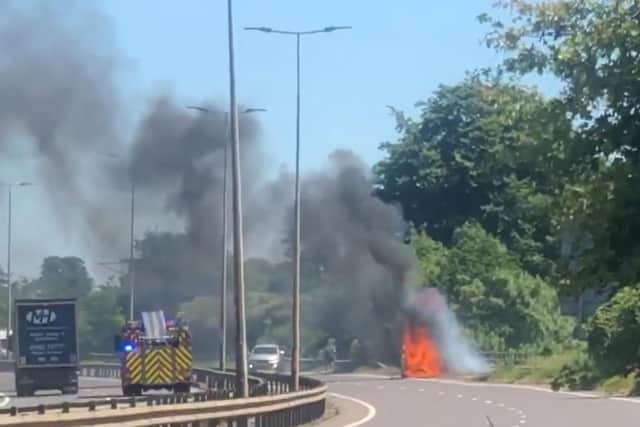 The vehicle is well ablaze as firefighters rush to the scene on the A45