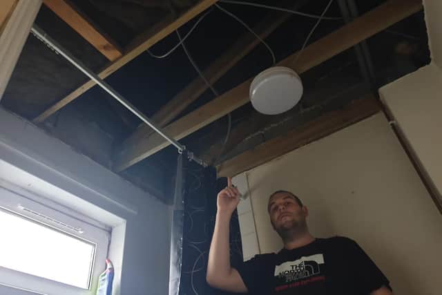 James Collingwood pointing with his ripped out bathroom ceiling