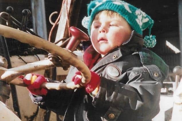 Riding on a tractor aged two.