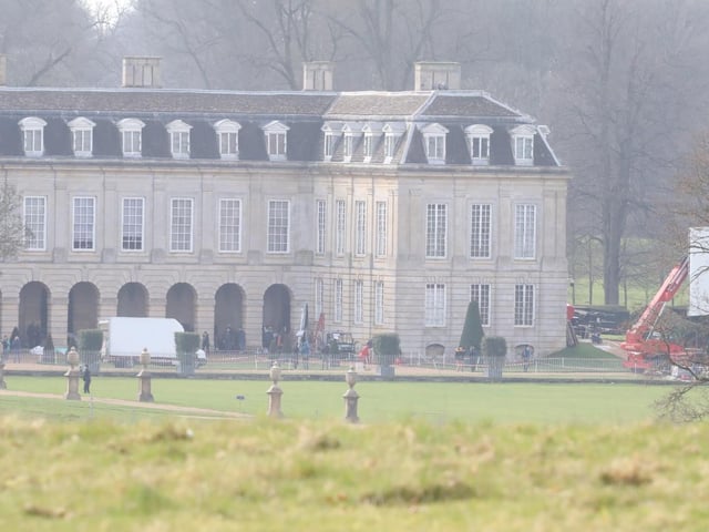 Large cranes carrying lighting rigs can be seen outside the house