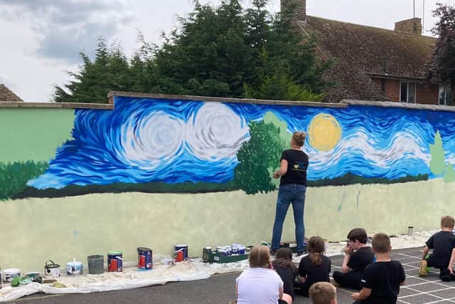 Local artist, Sarah Hodgkins, working on the mural as pupils watch on.