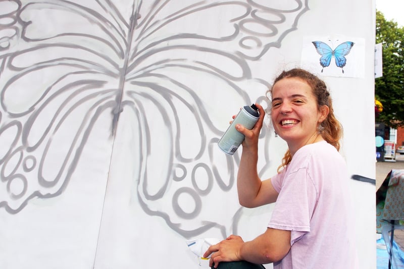 Zara Wilkins about to spray paint a butterfly onto the insect themed mural for Littlehampton town centre. Photo by Derek Martin Photography