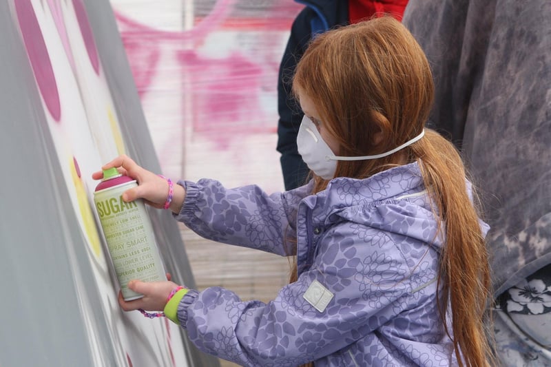 Esme Morter, age 11, spray painting the mural with non-toxic spray paints. Photo by Derek Martin Photography
