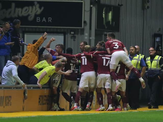 The Cobblers players and supporters celebrate Jon Guthrie's match winning goal (Pictures: Pete Norton)