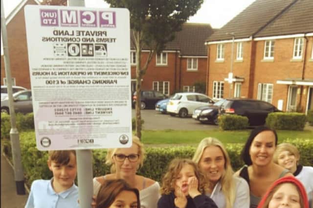 Brownlee Place residents celebrating next to the parking permit sign which went up in their street