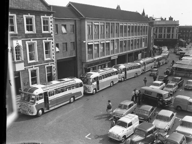 At least eight Wesleys coaches gather on Northampton Market Square to take passengers on an outing. Outside the Peacock Way arcade. September 10, 1964