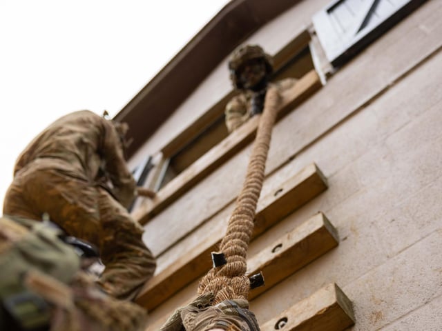 Private Henry (window) from 2nd Battalion The Royal Anglian Regiment looks down to help his colleague climb the rope wall during the Confidence Course run in Copehill Down.This is part of the Regiment's build up training ahead of their deployment onto Exercise Wessex Storm.