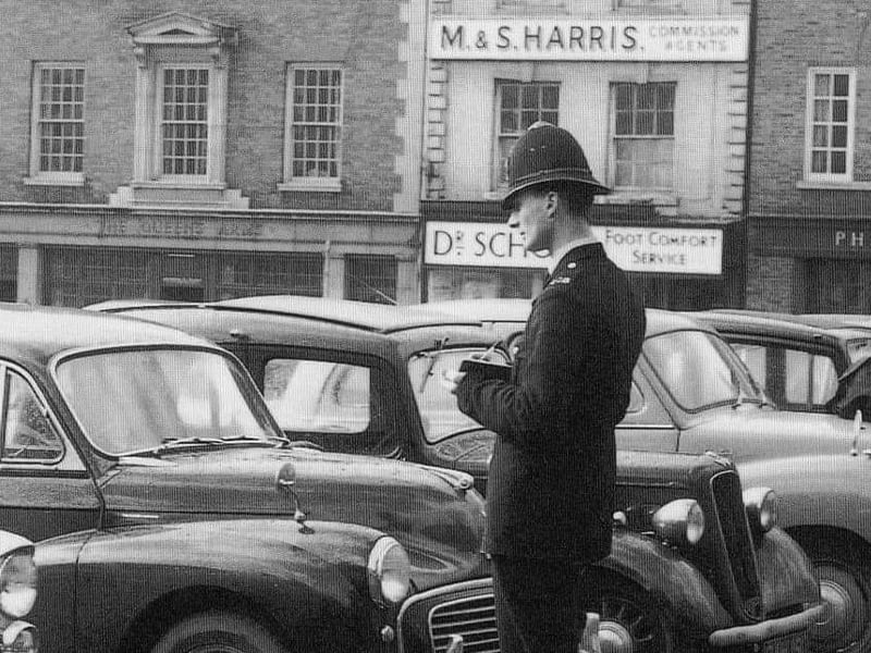 A police officer inspects a car on the Market Square. Circa 1960s.