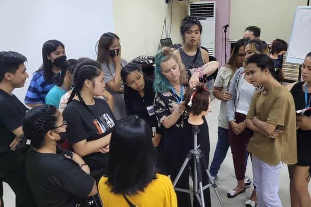 Jade,hair stylist, in action teaching her pupils basic hairdressing skills