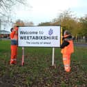 Workmen installing a Welcome to Weetabixshire sign