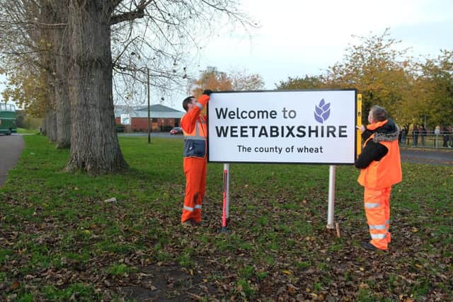 Workmen installing a Welcome to Weetabixshire sign