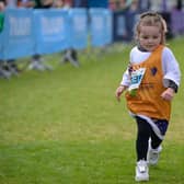 Girl running in Junior's Race with charity bib on