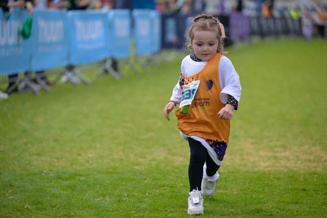 Girl running in Junior's Race with charity bib on