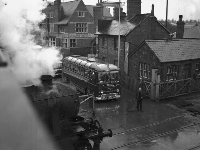 Bus waiting at level crossing for steam train