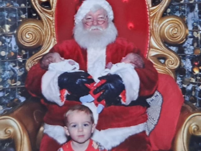 Five-week-old twins James and Edwards meeting Santa with their big brother Freddie on their first Christmas.