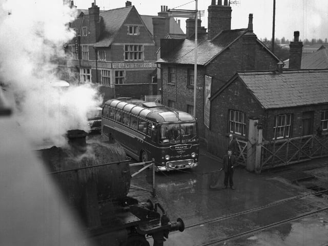 Bus waiting at level crossing for steam train
