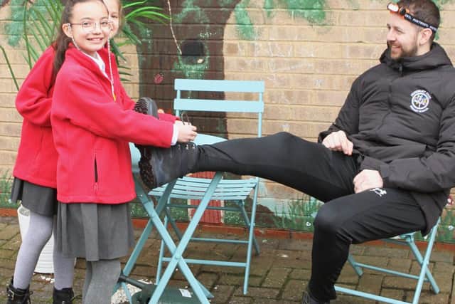 Pupils help Mr Dyson to lace his walking boots ready for the trek!
