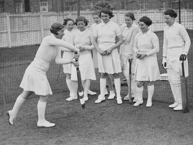 Cricketer Gwladys Joan Davis (1911 - 2004) from Wales, team captain and left-arm medium-fast bowler for the Northampton Ladies Cricket Club team, instructs players in the forward defensive stroke during batting practice in the nets on 6th May 1938 at Northampton cricket ground in Northampton, England. (Photo by Fox Photos/Hulton Archive/Getty Images)
