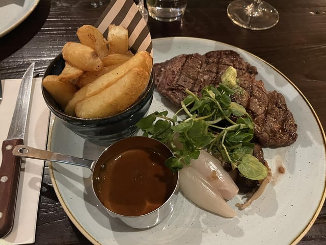 30 day-aged 10oz rib-eye steak, served with rustic thick-cut chips, beef dripping pangrattato shallots, exotic mushrooms, parsley butter and beef dripping sauce.