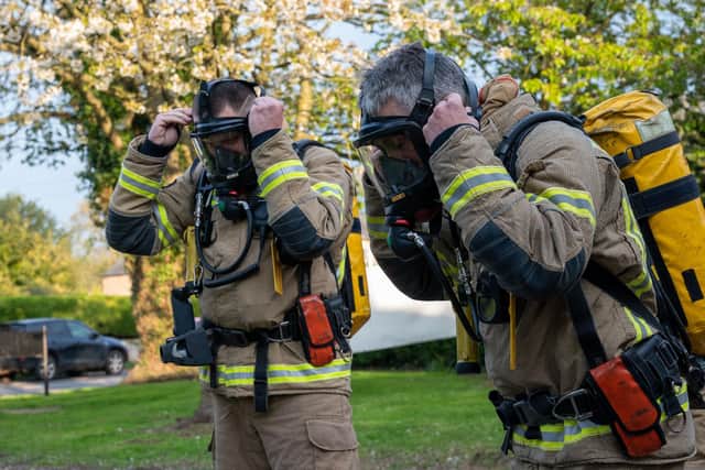 Two firefighters putting on their kit