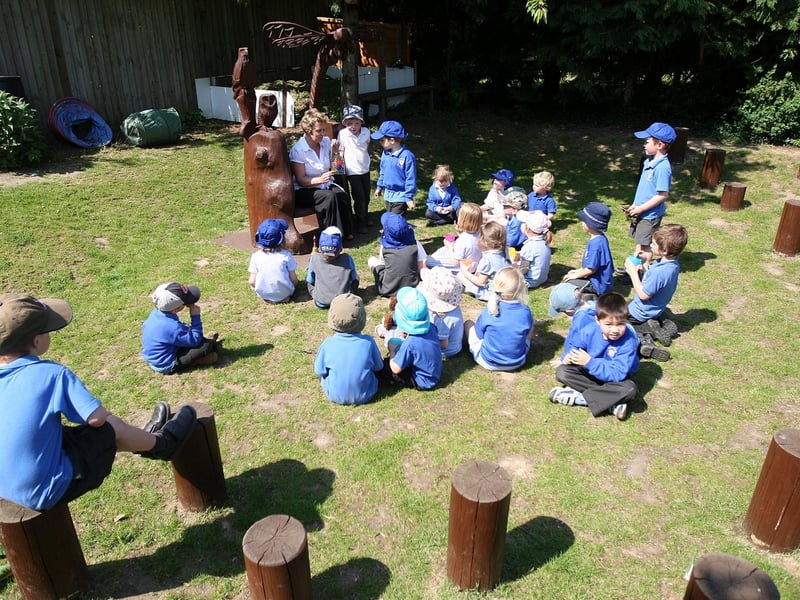 Children playing and enjoying outdoor activities at The Bliss Charity School, including having a story around storyteller's chair in the walled garden and traditional games in the playground at the front of the school.