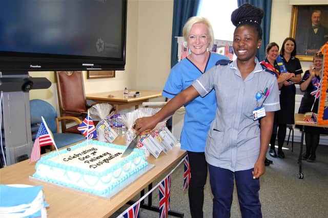 Dame Ruth May and Staff Nurse Fummi Yakubu cutting a celebration cake.
