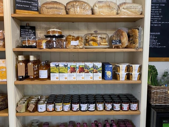 Local produce, bread, cakes, and cupboard essentials are pictured inside the shop.