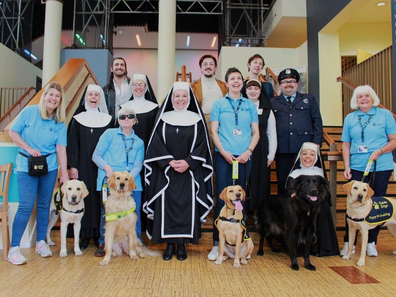Cast members from Sister Act The Musical with volunteers and dogs from Guide Dogs