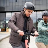 Two people riding Voi e-scooters