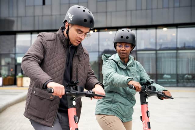 Two people riding Voi e-scooters