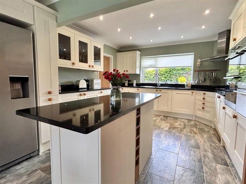 A large kitchen with an island surface boasts the best of modern and traditional living