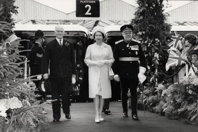 The Queen arrives at Kettering Station accompanied by stationmaster Mr J.A. Kind and Earl Spencer for a royal visit to the area on July 9, 1965