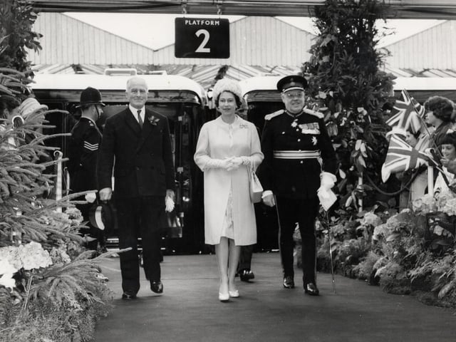 The Queen arrives at Kettering Station accompanied by stationmaster Mr J.A. Kind and Earl Spencer for a royal visit to the area on July 9, 1965