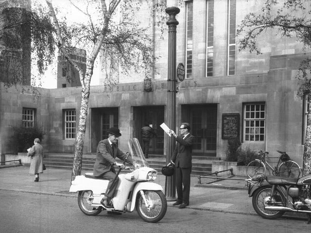 Worker on an enclosed Velocette motorcycle outside the Mounts Baths, Northampton